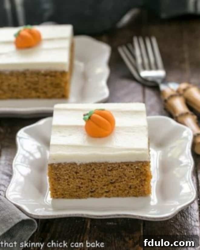 Spiced Pumpkin Bars with Cream Cheese Frosting 2 Two pumpkin bars with cream cheese frosting and candy pumpkins on white dessert plates, garnished with small decorative pumpkins.