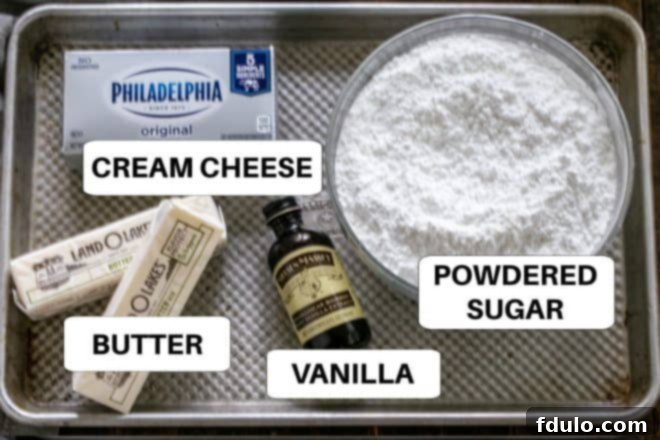 Spiced Pumpkin Bars with Cream Cheese Frosting 4 Ingredients for cream cheese frosting laid out on a metal tray with labels including cream cheese, butter, vanilla, and powdered sugar.