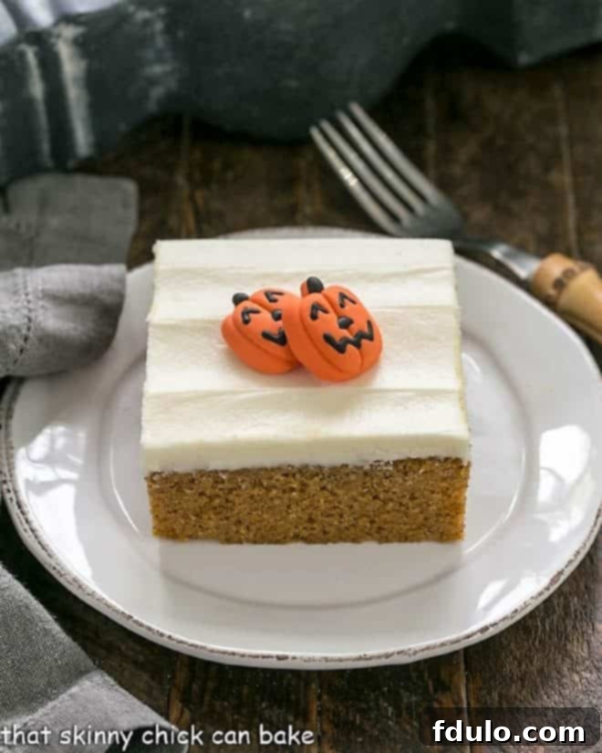 Spiced Pumpkin Bars with Cream Cheese Frosting 8 One pumpkin bar with cream cheese frosting, garnished with a small decorative sugar pumpkin, on a round white dessert plate.