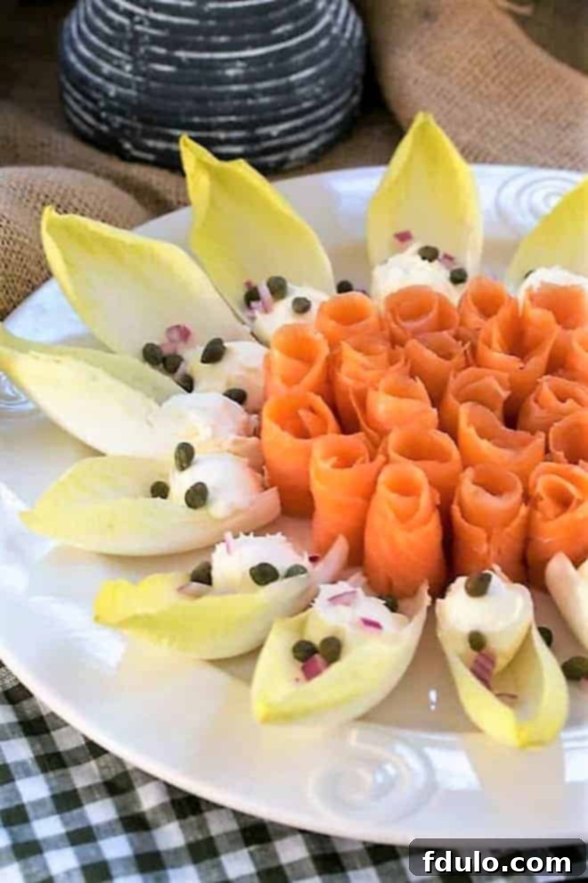 Smoked salmon roses- arranged on a white serving plate with endive, creme fraiche, capers and red onion, garnished with fresh dill.