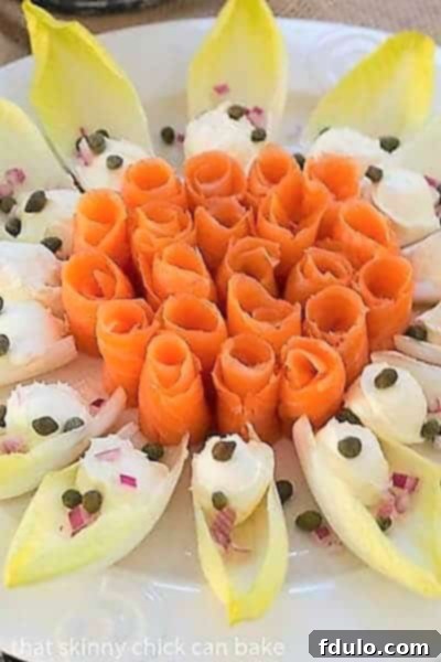 Close view of Smoked Salmon Roses with Endive and Creme Fraiche on a smoked salmon platter, garnished with capers and red onion.