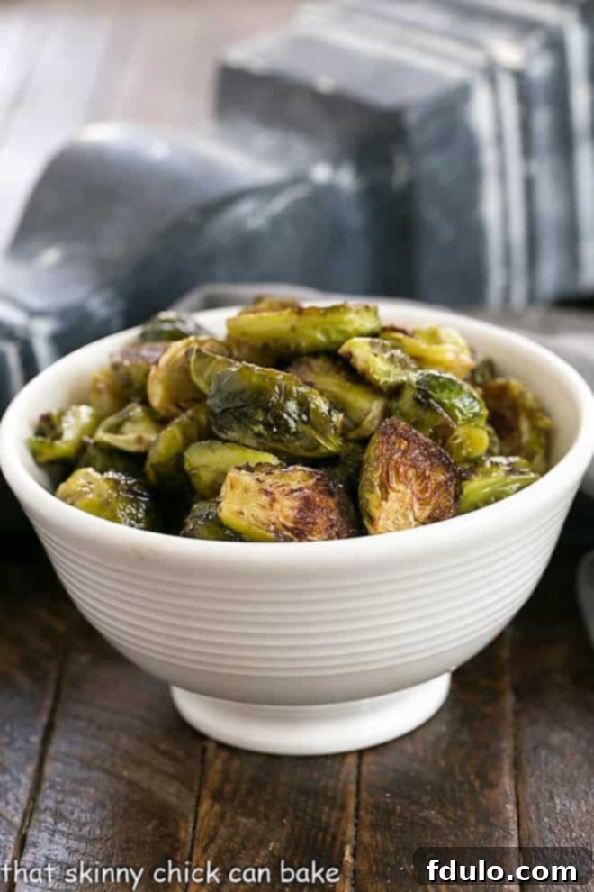 Honey Balsamic Brussels Sprouts - Turn these once dreaded vegetables into one amazing side dish by roasting a tossing in a vinaigrette Honey Balsamic Brussels Sprouts in a white serving bowl, glistening with sauce.