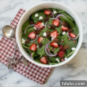 A vibrant bowl of Spinach, Strawberry, Pomegranate, and Feta Salad, ready to be served.