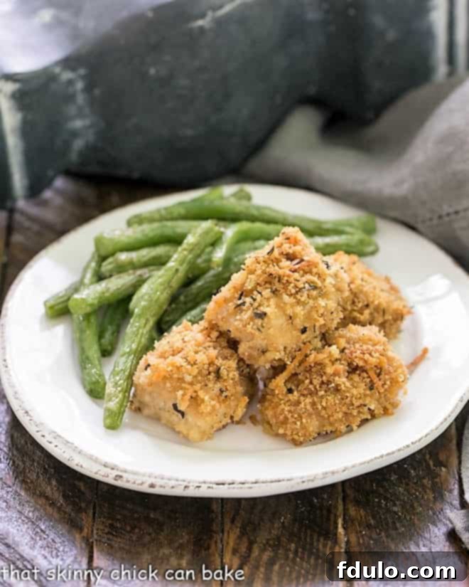 The Ultimate Homemade Chicken Nuggets 9 homemade chicken nuggets on a white plate with roasted green beans