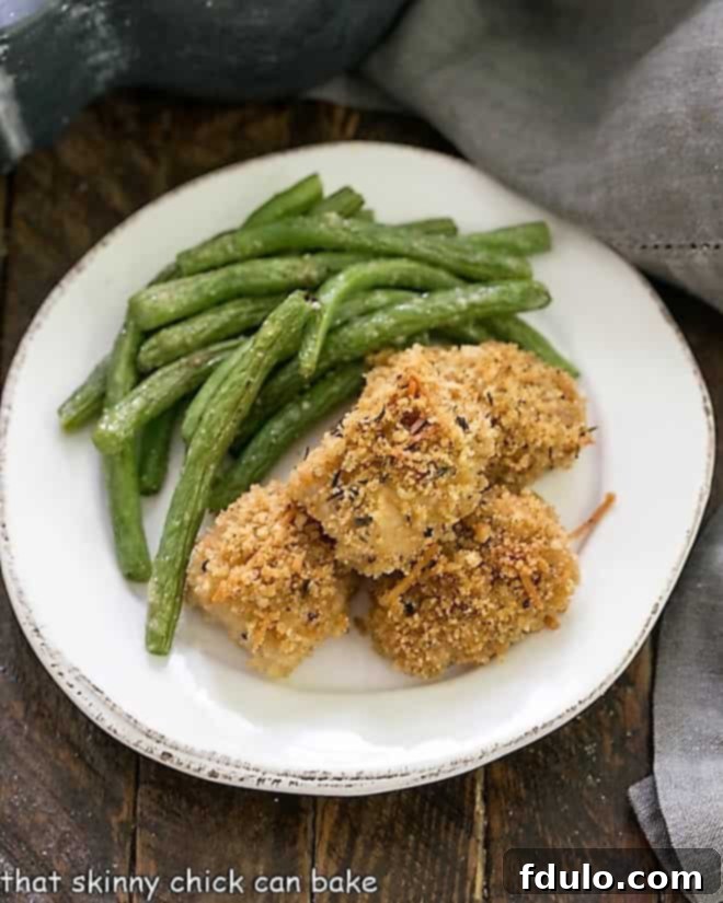 Homemade Chicken Nuggets Recipe - Ditch the drive-through and make homemade chicken nuggets for your family! overhead view of homemade chicken nuggets on a round white plate with a side of vibrant green beans.