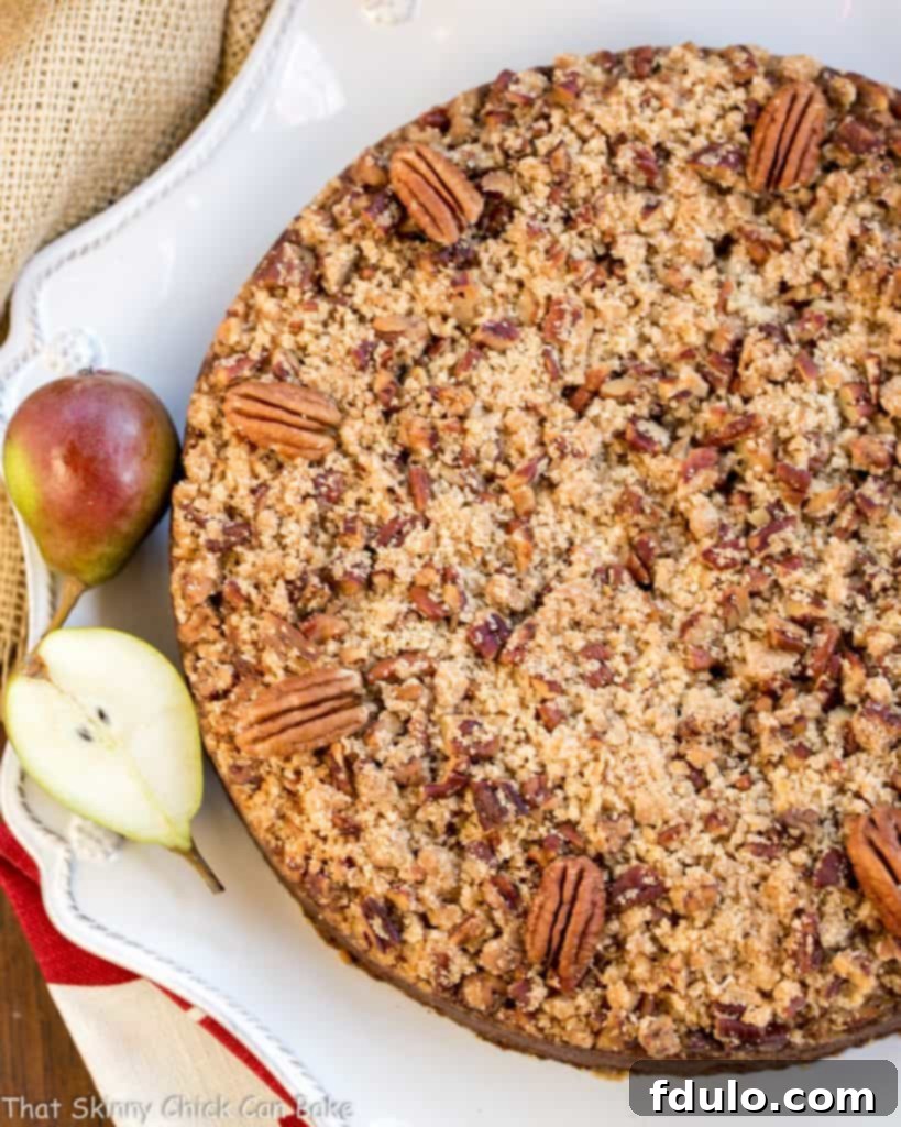 Pear Streusel Coffee Cake viewed from above on a white serving dish with small fresh pears - a comforting homemade dessert