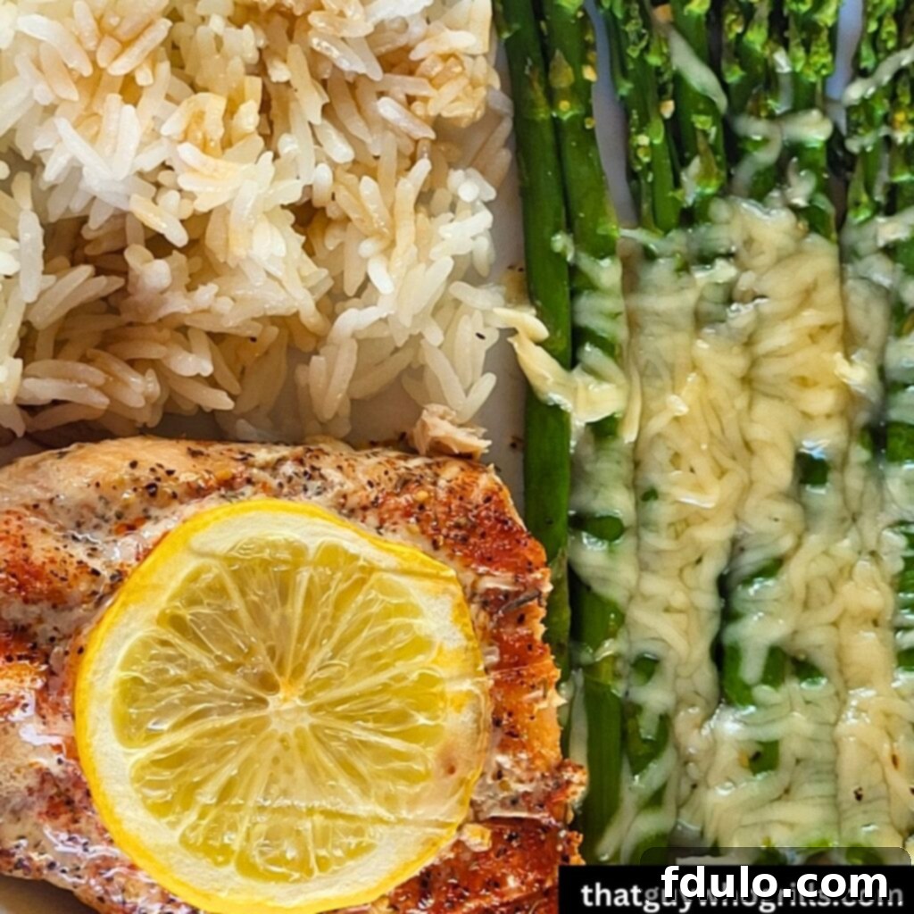 White rice with grilled salmon served with cheesy grilled asparagus on a white plate