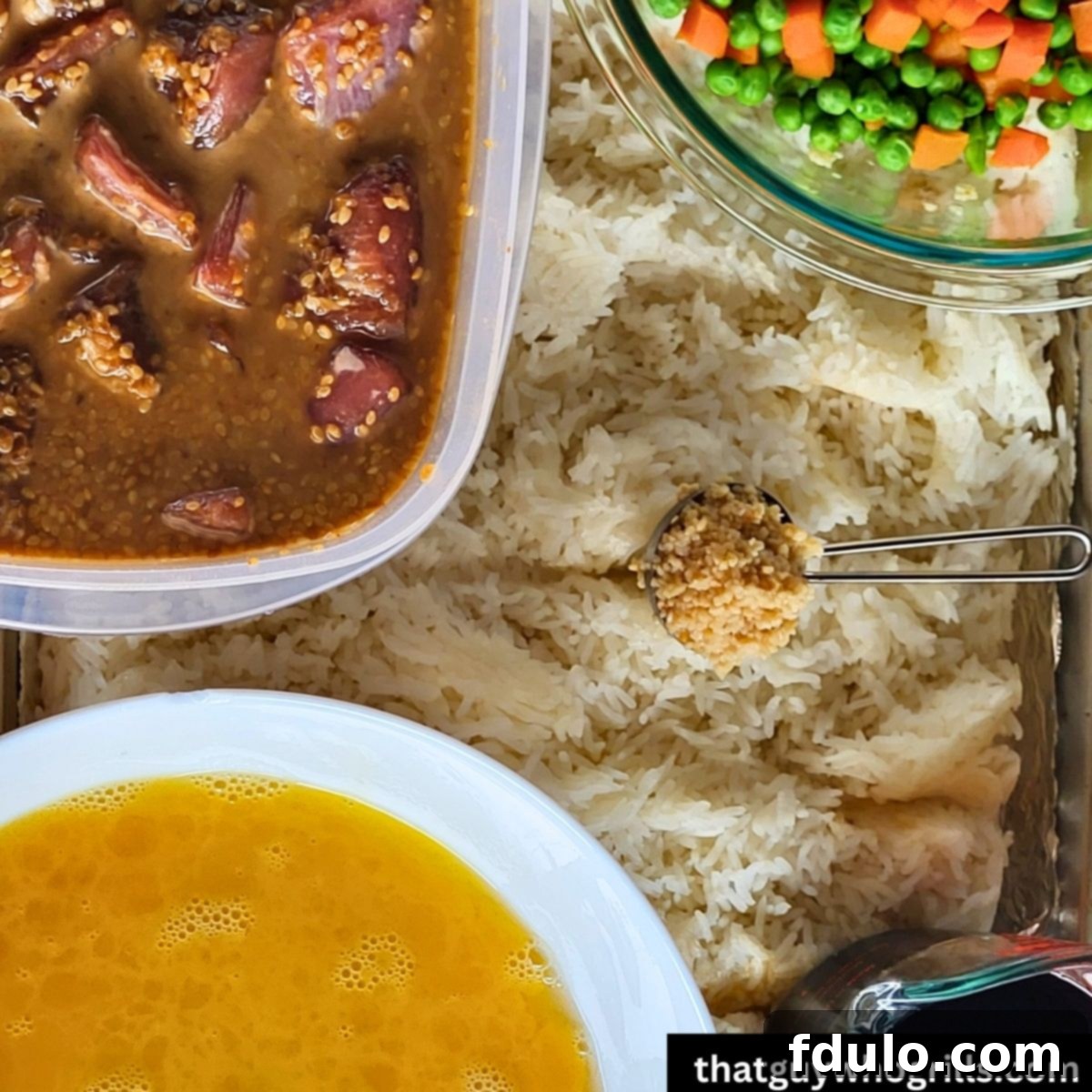 All ingredients laid out: white rice, whisked eggs, marinated pork, peas and carrots, and minced garlic on a baking sheet, ready for the Blackstone griddle to create Teriyaki Pork Fried Rice.