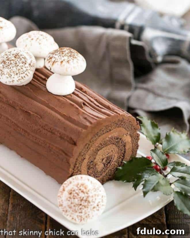 A beautifully decorated Bûche de Noël, or Yule Log cake, featuring chocolate ganache and festive edible garnishes.
