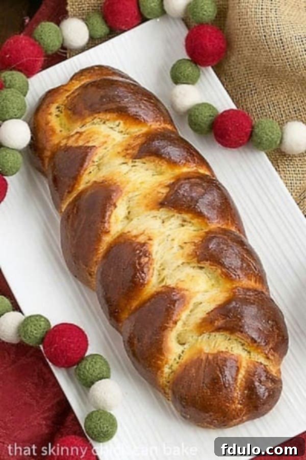 Overhead view of a perfectly golden, braided loaf of Swiss Butter Braid (Butterzopf) resting on a white platter.