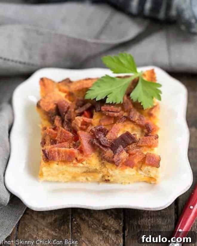 A close-up of a single slice of Bacon and Egg Strata on a small white plate, highlighting the crispy top and layers within.