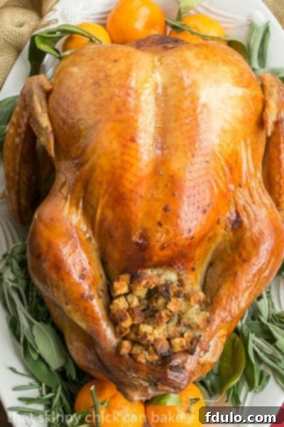 Overhead view of a perfectly roasted Dry Brined Turkey garnished with fresh sage, rosemary, and orange slices, ready for carving.