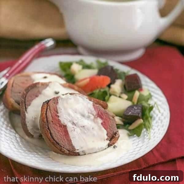 Tender slices of Beef Tenderloin, each topped with a generous dollop of creamy Gorgonzola Sauce, arranged artfully on a white plate.