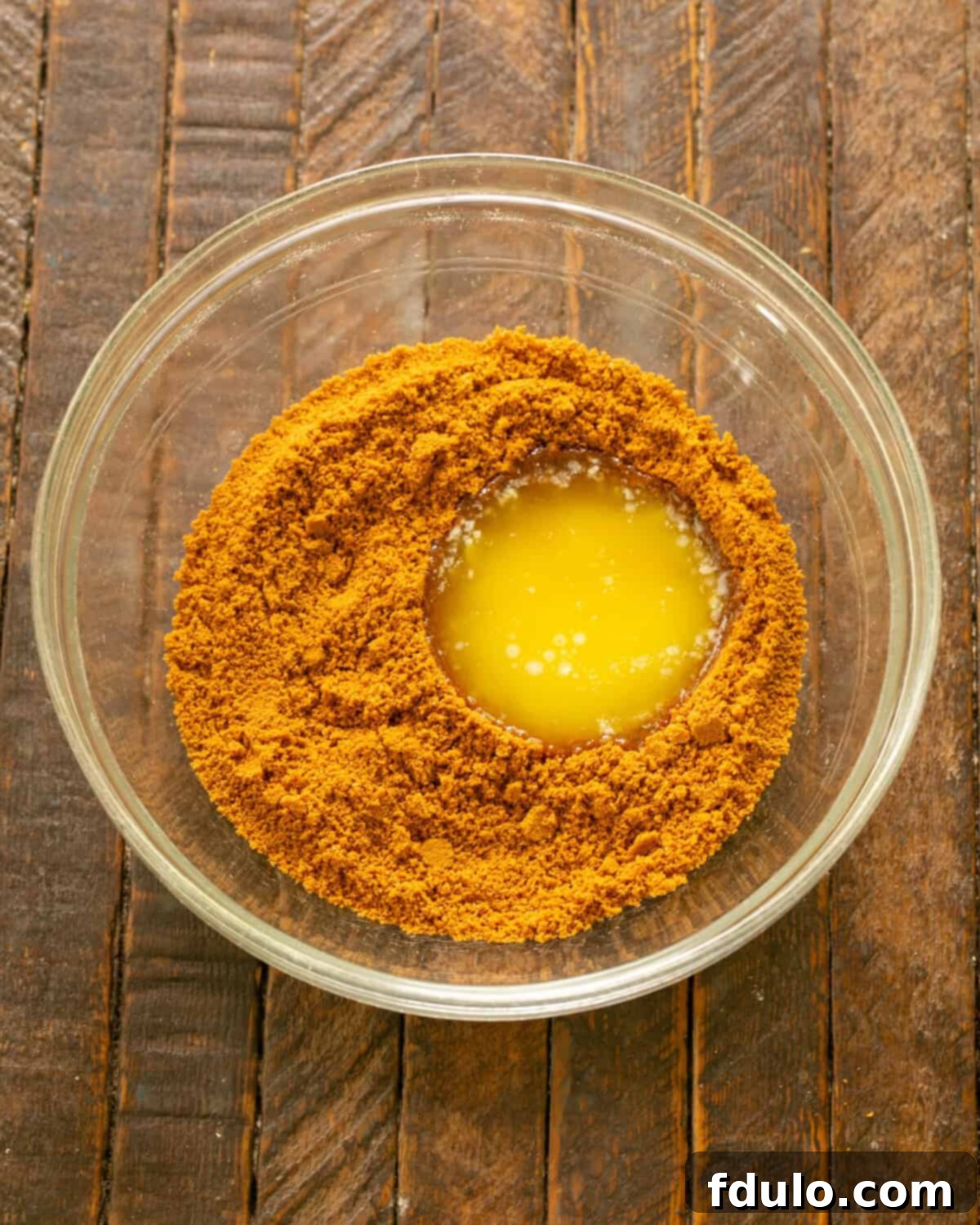 Add melted butter to crushed Biscoff cookie crumbs in a bowl.