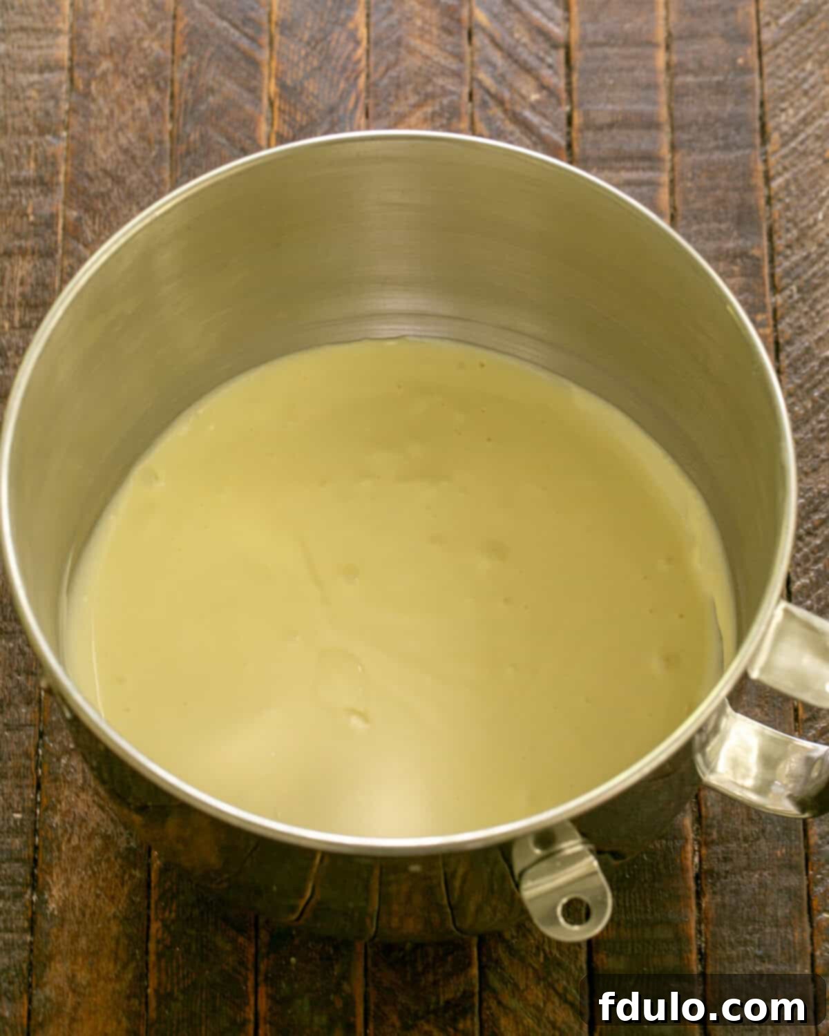 Mixing ingredients for creamy cheesecake batter in a stand mixer.