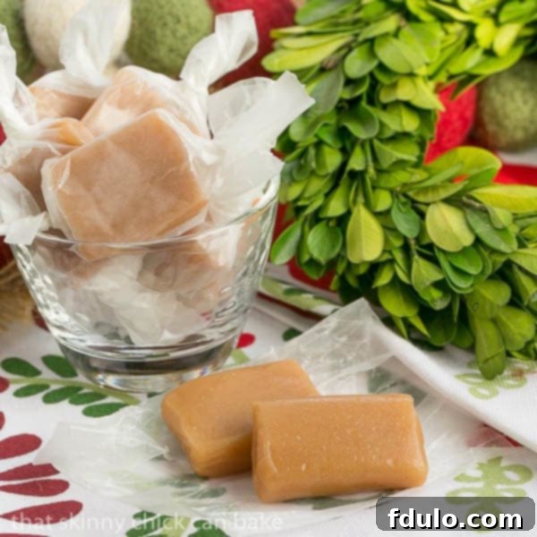 Two unwrapped Soft Vanilla Caramels artfully placed in front of a generous glass bowl overflowing with more golden caramels, inviting you to indulge.