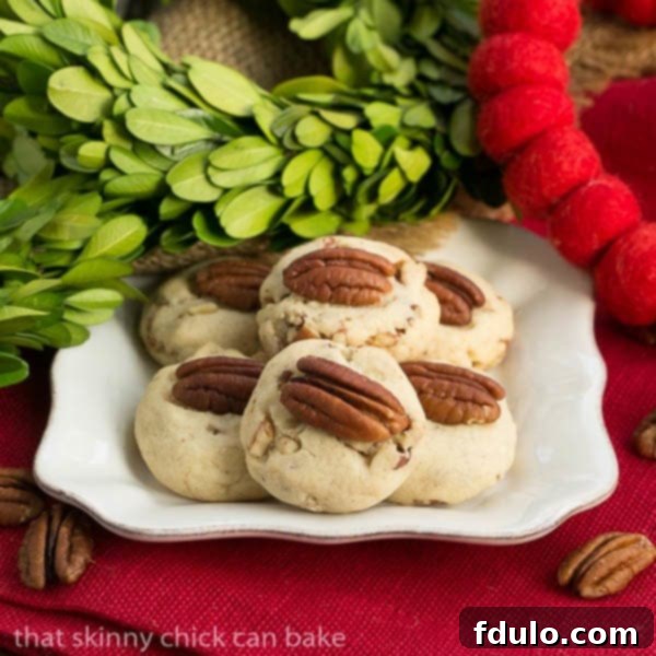Pecan Sandies on a square white dessert plate, featuring a whole pecan in the center, highlighting their rustic charm.