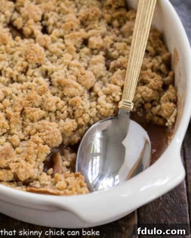 Apple crisp in a baking dish with one serving removed, showing the soft apples underneath.