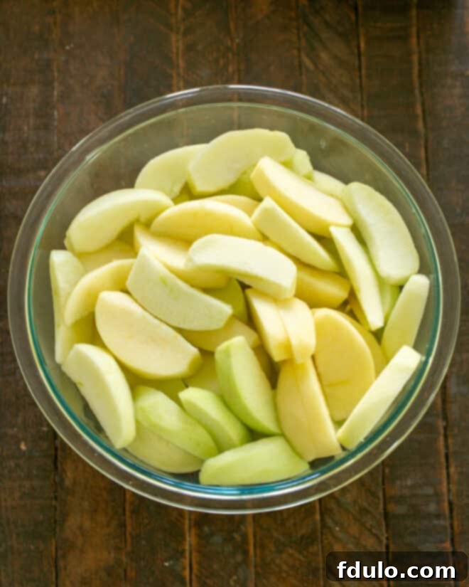 Apples sliced uniformly for apple crisp, piled in a large bowl.