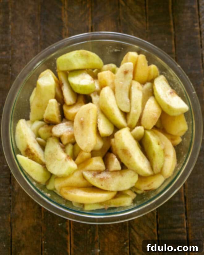 Apple crisp filling mixed, with apples evenly coated in sugar and spices.