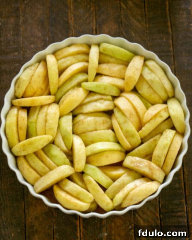 Mixed apples evenly distributed in a baking dish, forming the base of the crisp.