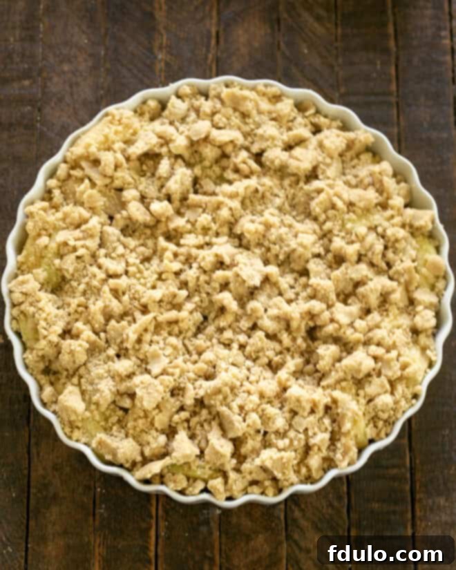 Apple crisp with crumbly streusel topping evenly distributed over the apples.