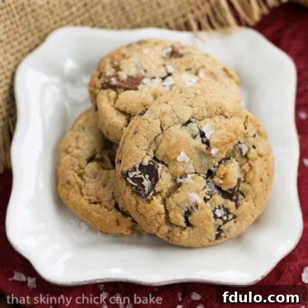 Indulge in the rich flavors and perfect texture of these Salted Toffee Chocolate Chunk Cookies, a delightful treat for any occasion. Salted Toffee Chocolate Chunk Cookies arranged neatly on a square white plate