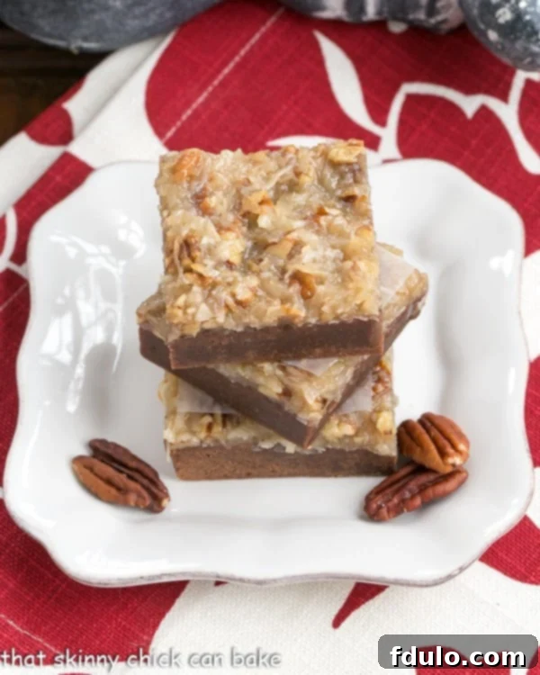 German Chocolate Brownies - fudgy brownies with a gooey pecan coconut topping Close-up of a square German Chocolate Brownie on a white plate, garnished with pecan halves, showcasing the fudgy base and the rich, gooey coconut and pecan topping.