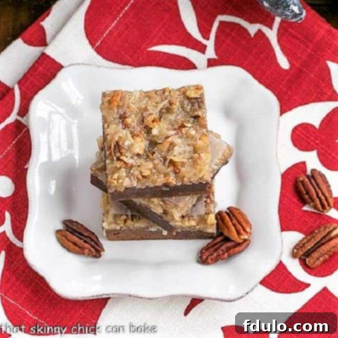 German Chocolate Brownies - Fudgy brownies topped with a caramelly, coconut, pecan topping Overhead view of a stack of German Chocolate Brownies on a square white plate, with extra pecan halves scattered around for garnish.