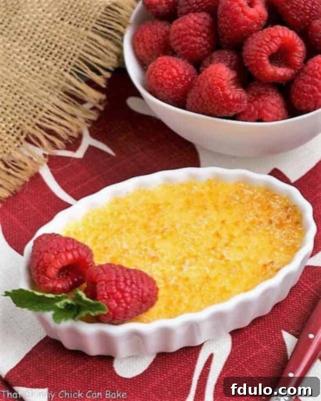 Classic Crème Brûlée in a white ramekin with a raspberry garnish.