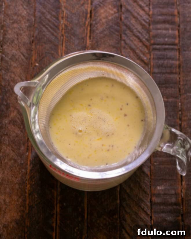 Heavenly Crème Brûlée Perfection 7 Straining the custard mixture into a clean bowl or measuring cup.