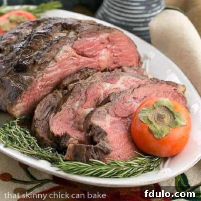 Perfectly sliced Classic Prime Rib roast on a white platter, garnished with rosemary and persimmon, ready to serve.
