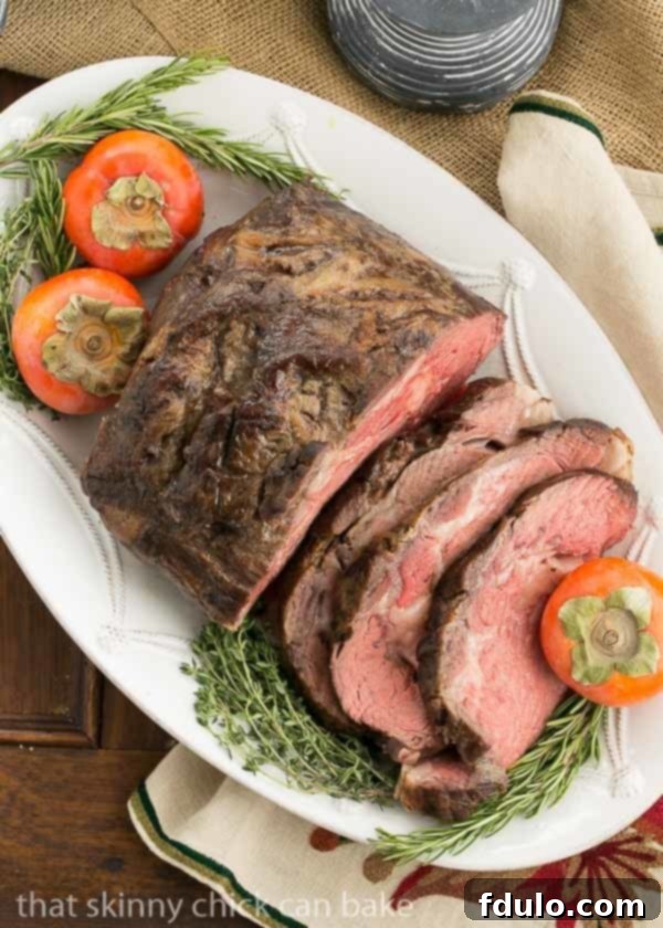 Overhead view of a beautifully cooked Classic Prime Rib, partially sliced to reveal a perfect medium-rare interior, adorned with fresh herbs and fruit.