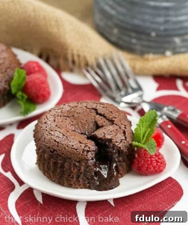 Chocolate Lava Cakes broken open with the fudgy centers exposed on a white dessert plate.