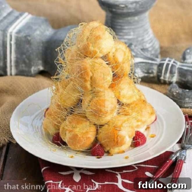 Lemon Cream Croquembouche on a white serving plate garnished with fresh raspberries and spun sugar.
