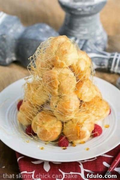 Lemon Cream Croquembouche wrapped in spun sugar on a white serving plate.