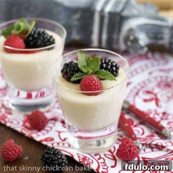 Two servings of Vanilla Bean Panna Cotta garnished with fresh berries and a sprig of mint, showcasing a beautiful dessert presentation.