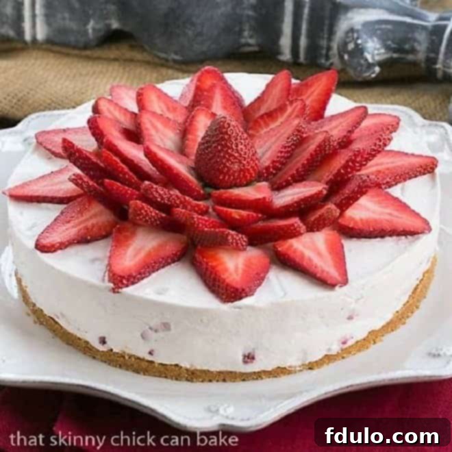 A pristine Strawberry Vanilla Cream Pie adorned with an artful arrangement of fresh strawberry slices, presented on an elegant white Juliska serving plate, ready to be enjoyed.