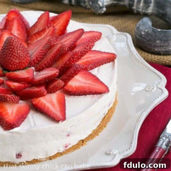 A close-up view of half a Strawberry Vanilla Cream Pie on a pristine serving dish, highlighting the layers of creamy filling, graham cracker crust, and fresh strawberry topping, ready for a delightful bite.
