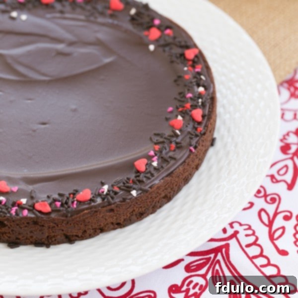 Uncut Ganache Topped Truffle Brownies, perfectly set on a white plate, ready to be sliced and served.