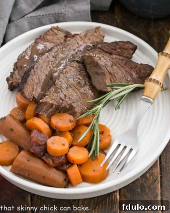 Rosemary Garlic Brisket slices on a white plate with a bamboo fork.