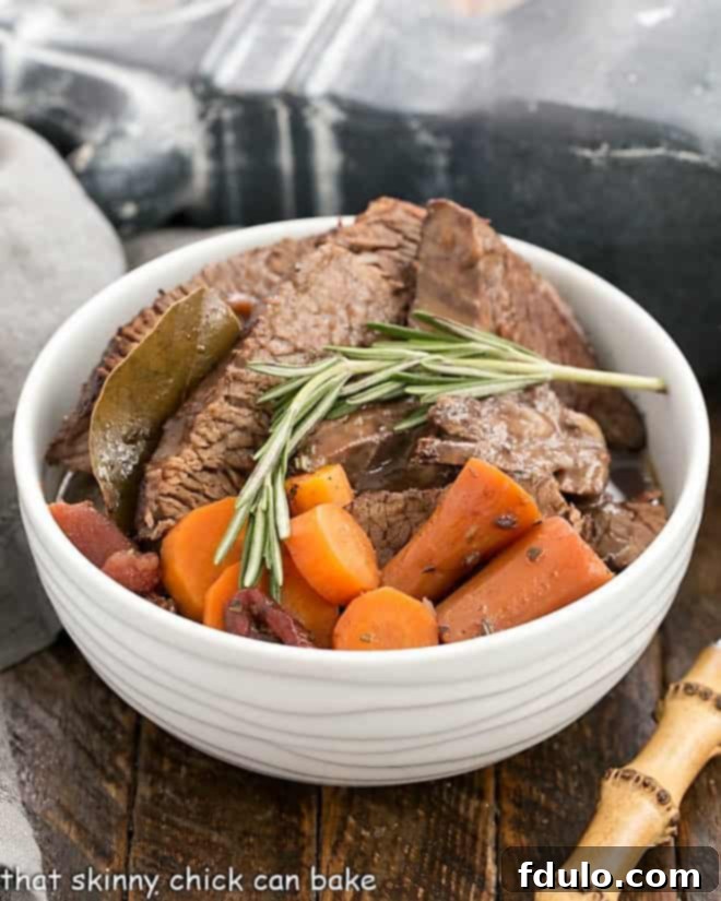Rosemary Garlic Brisket in a white ceramic bowl with carrots and rosemary