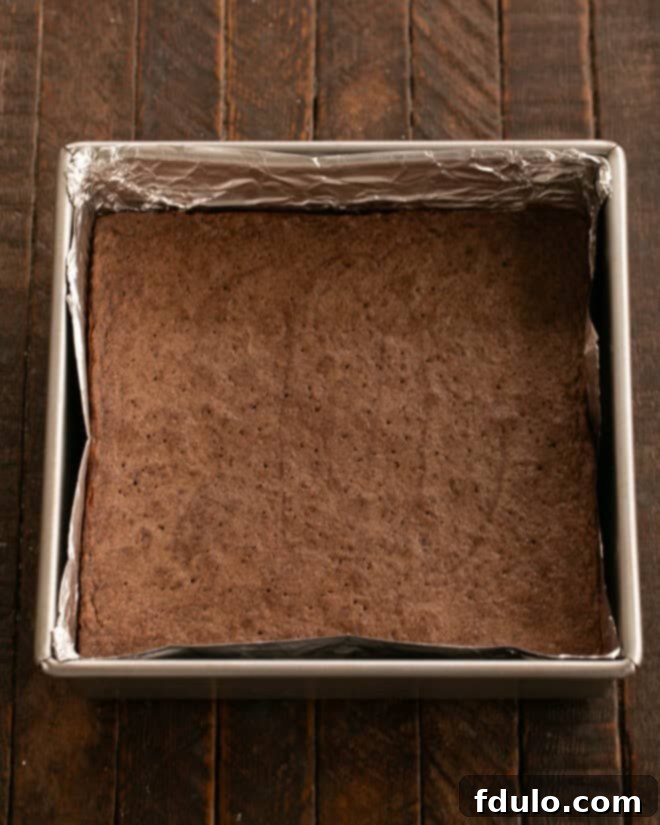 Brownie batter spread evenly into the prepared baking pan.