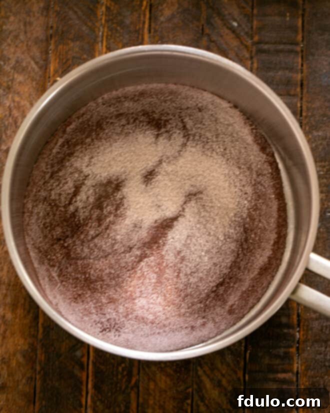 Whisking dry ingredients in a saucepan for chocolate pudding.