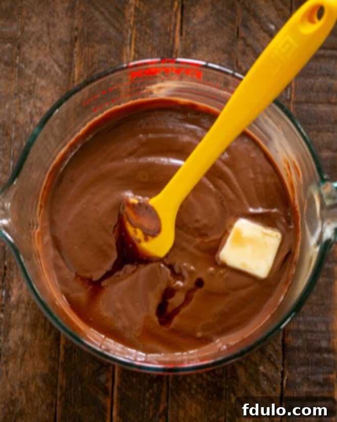 Stirring butter and vanilla extract into the strained chocolate pudding.