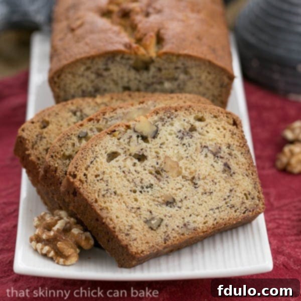 A delicious loaf of Classic Banana Nut Bread with slices, presented on a white tray.