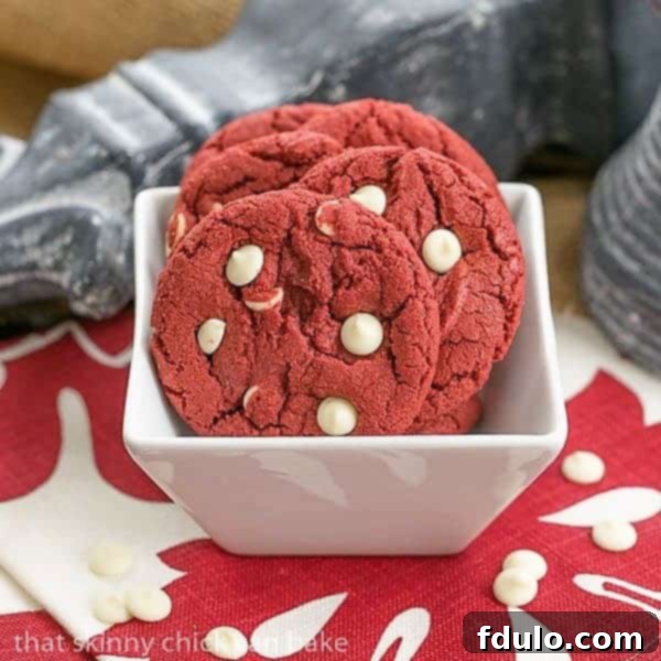 A close-up shot of vibrant Red Velvet Cookies with White Chocolate Chips artfully arranged in a square white bowl, showcasing their irresistible texture and rich color.