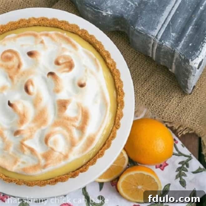 An overhead shot of the Meyer Lemon Tart with Meringue Topping, beautifully arranged on a white cake stand, highlighting its intricate swirls.