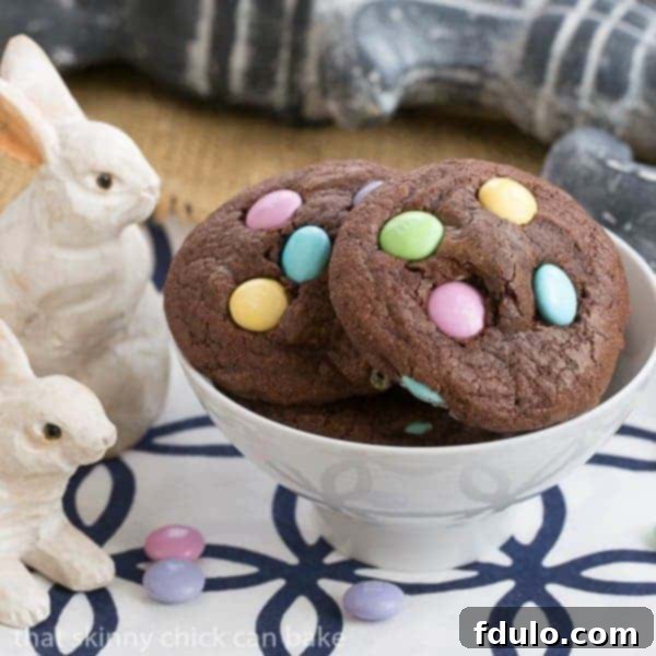 Easter Candy Brownie Cookies - Chewy Brownie Cookies speckled with leftover Easter candy Overhead view of 2 Easter brownie cookies with pastel M&Ms on a white surface, highlighting their homemade charm.