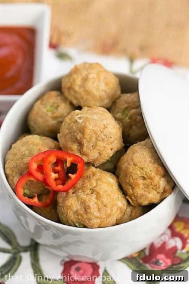 Sesame Ginger Chicken Meatballs in a stylish white lidded serving dish, perfect for keeping them warm at a party or gathering.